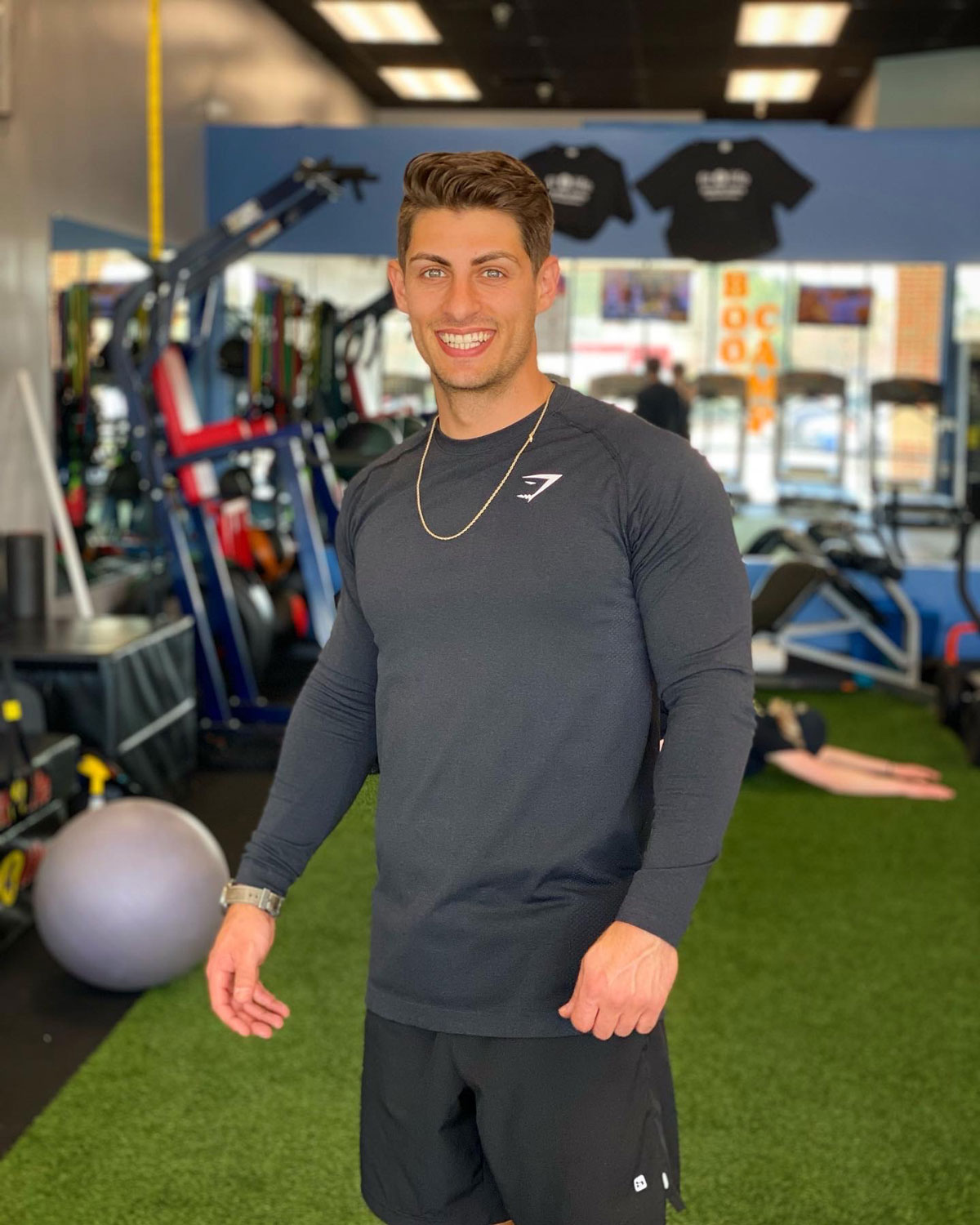 Partner of the coach, smiling, posing for a photo in a gym.